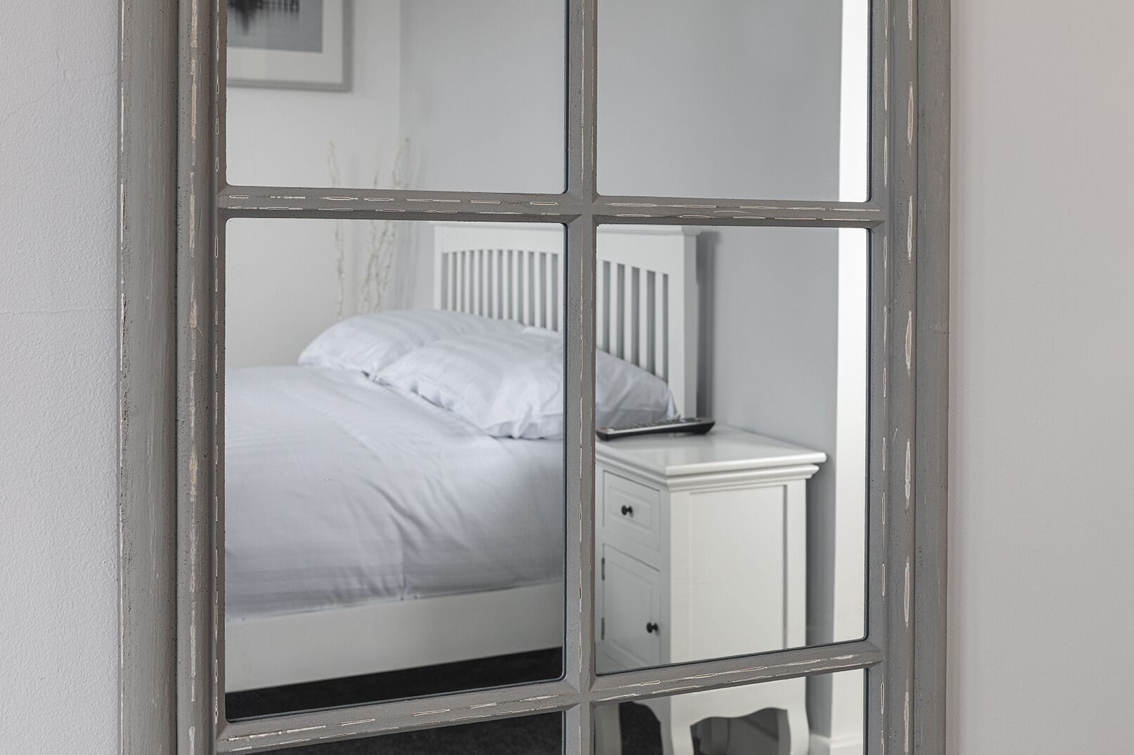 Quarto com uma cama, uma mesinha de cabeceira e um criado-mudo.