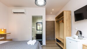 A modern hotel room with a bed, a small desk, a television, and a wardrobe.