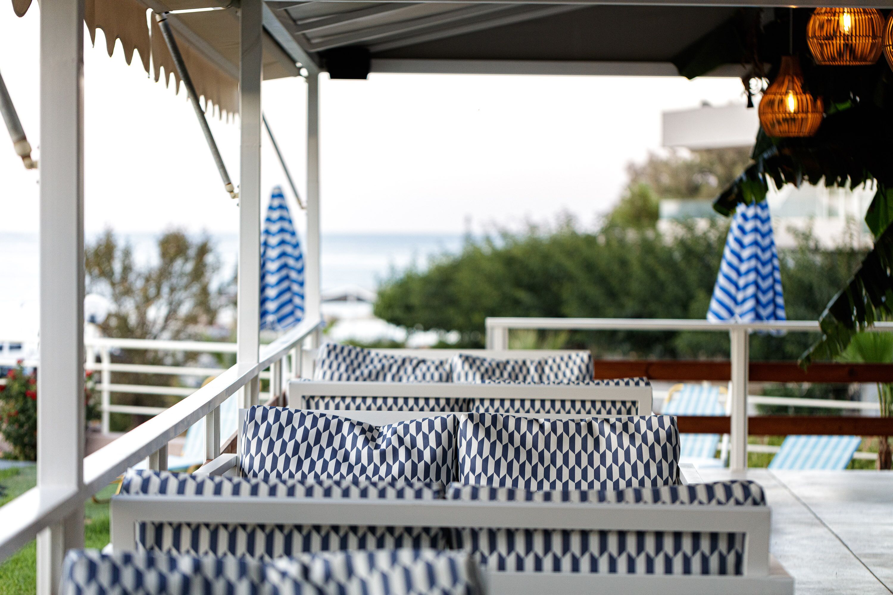 A covered outdoor seating area with patterned cushions and a view of the sea.