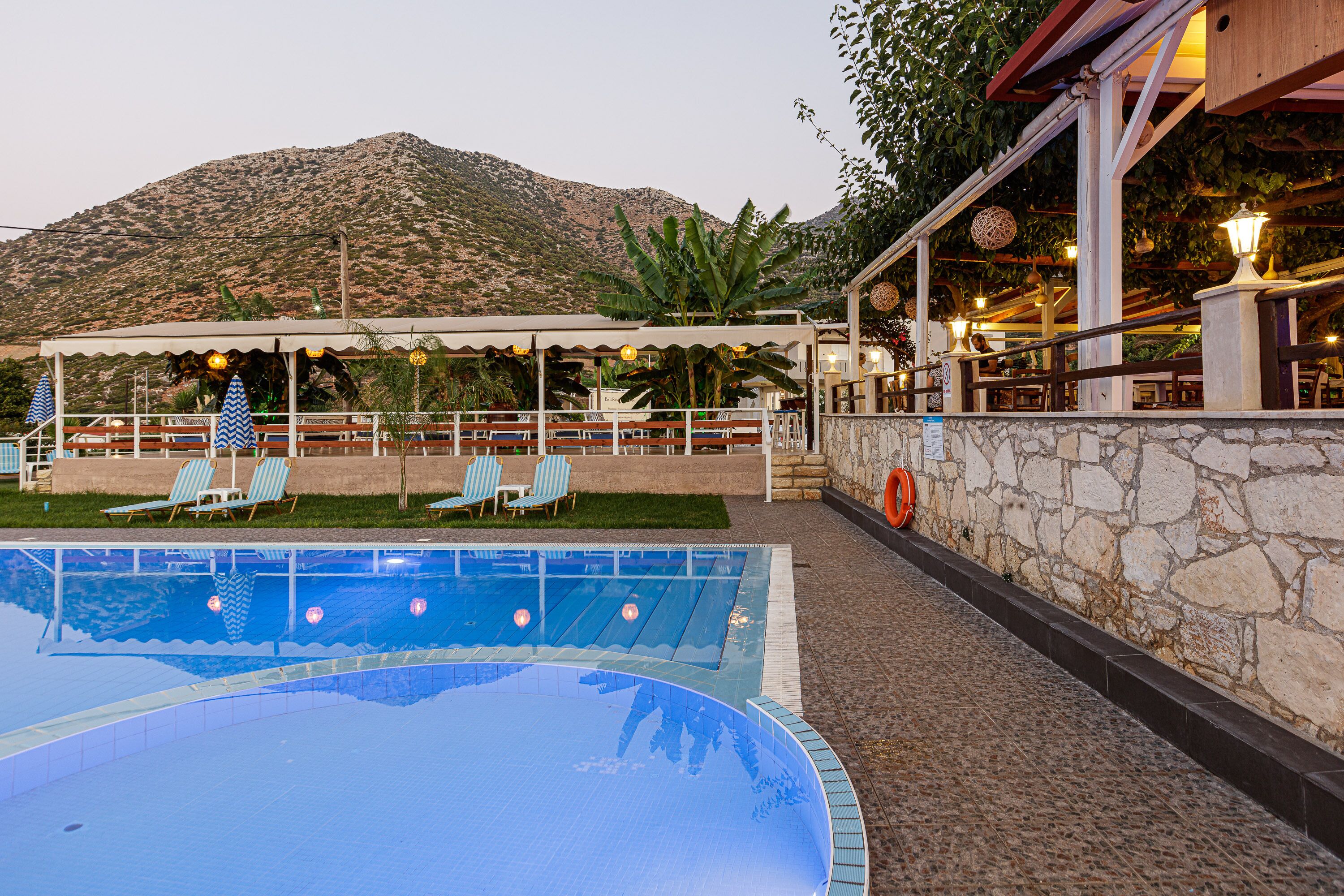 Un'area piscina con lettini e un muro in pietra.
