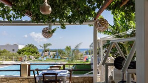 An outdoor seating area with a pool view, stone walls, and a pergola with hanging lights.