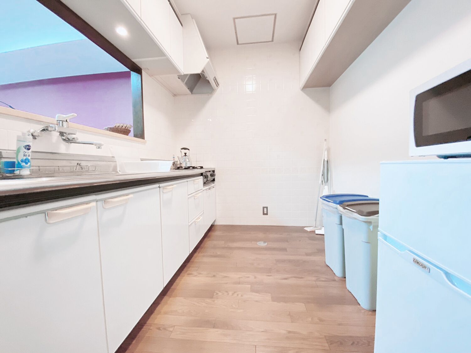 A modern kitchen with white cabinets, a wooden countertop, a built-in stove, and a window with a view.