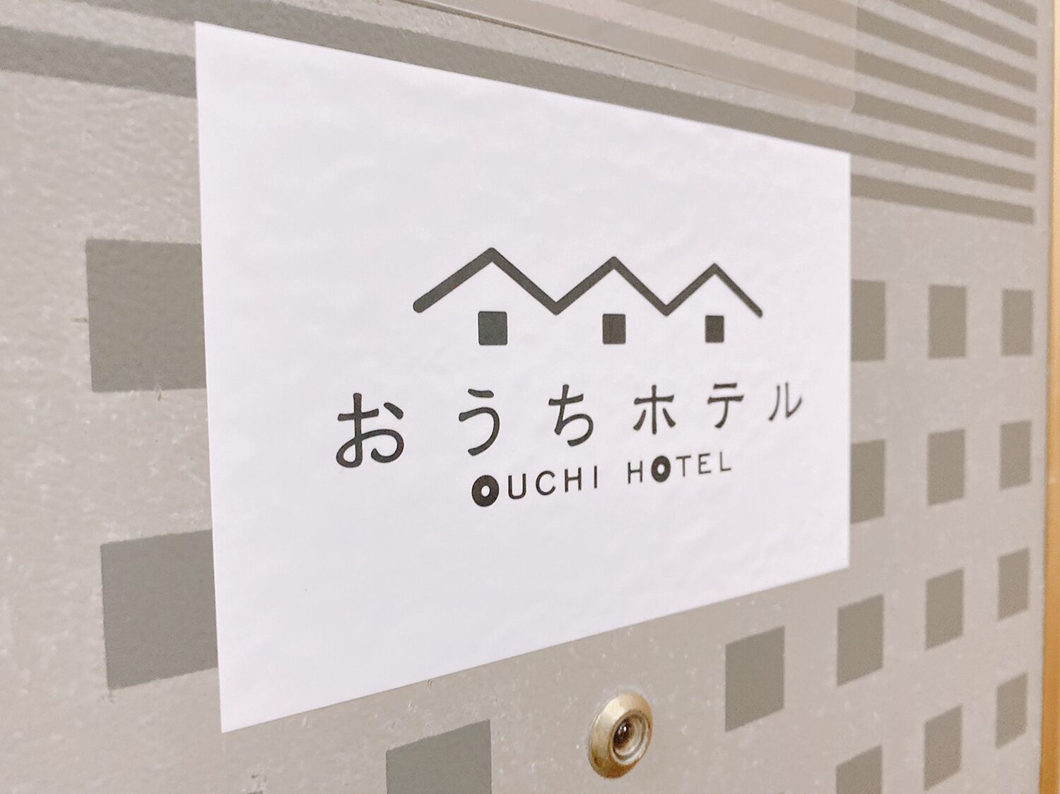 Un cartel de hotel con el nombre "Ouch! Hotel" y un icono sencillo de una casa.