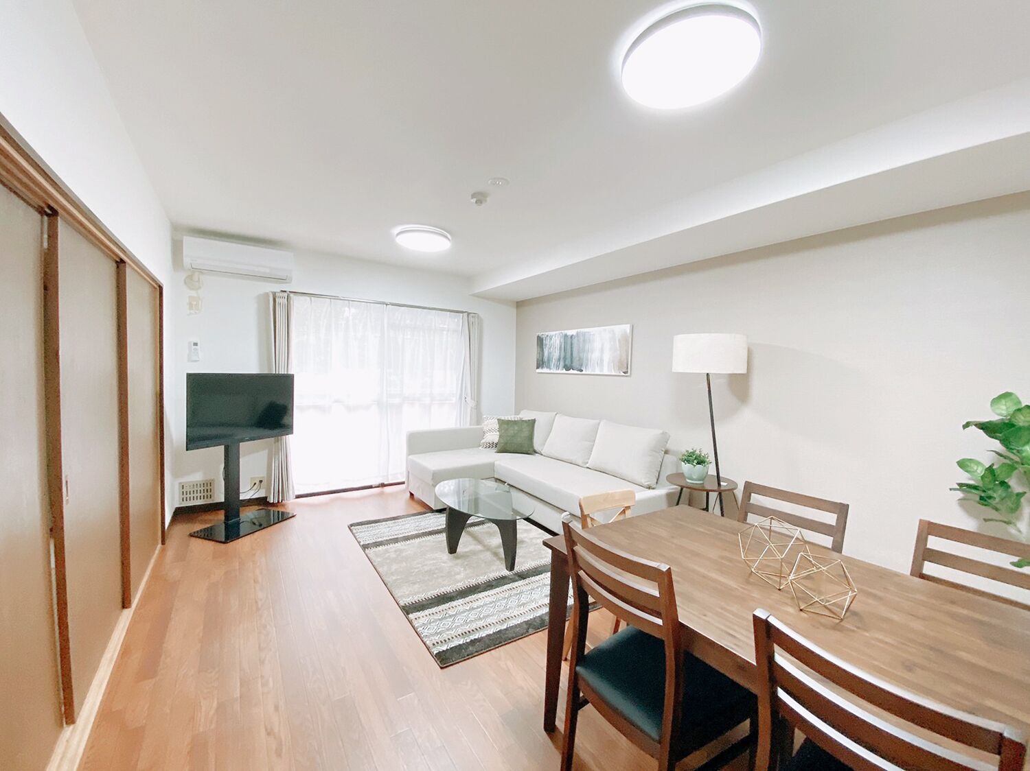 A modern living room with a sofa, a coffee table, and a dining table with chairs.