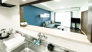 A modern kitchen with a large mirror, stainless steel sink, and a blue accent wall. - OUCHI HOTEL Itsukaichi (Hiroshima)