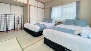 A hotel room with two beds, a traditional Japanese shoji screen, a tatami mat floor, and a large window with curtains. - OUCHI HOTEL Itsukaichi (Hiroshima)