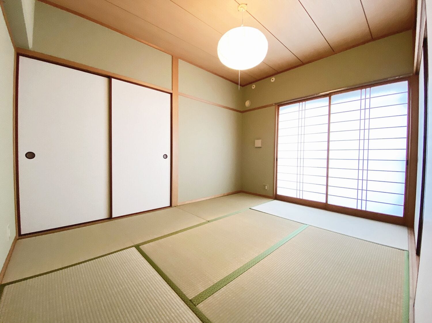 A traditional Japanese room with tatami flooring, sliding doors, and a large window with shoji screens.
