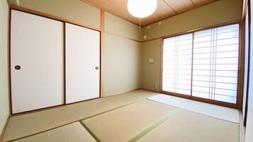 A traditional Japanese room with tatami flooring, sliding doors, and a large window with shoji screens.