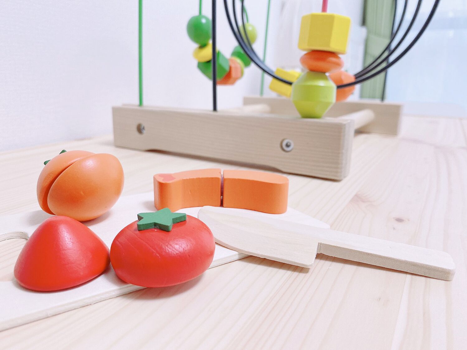A wooden play area with a hanging toy and a wooden structure with colorful blocks.