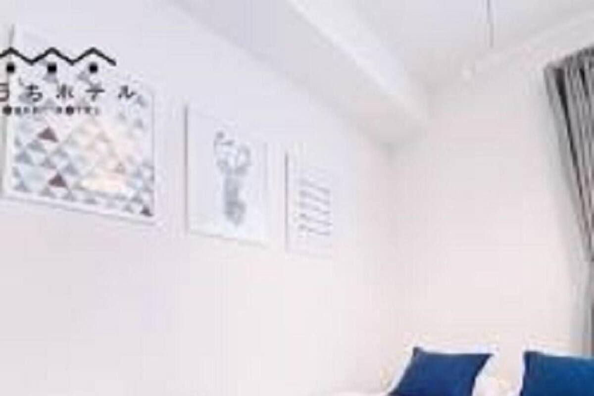 Une chambre d’hôtel avec un lit, des oreillers et une couverture. Les murs sont décorés et il y a une fenêtre avec des rideaux.