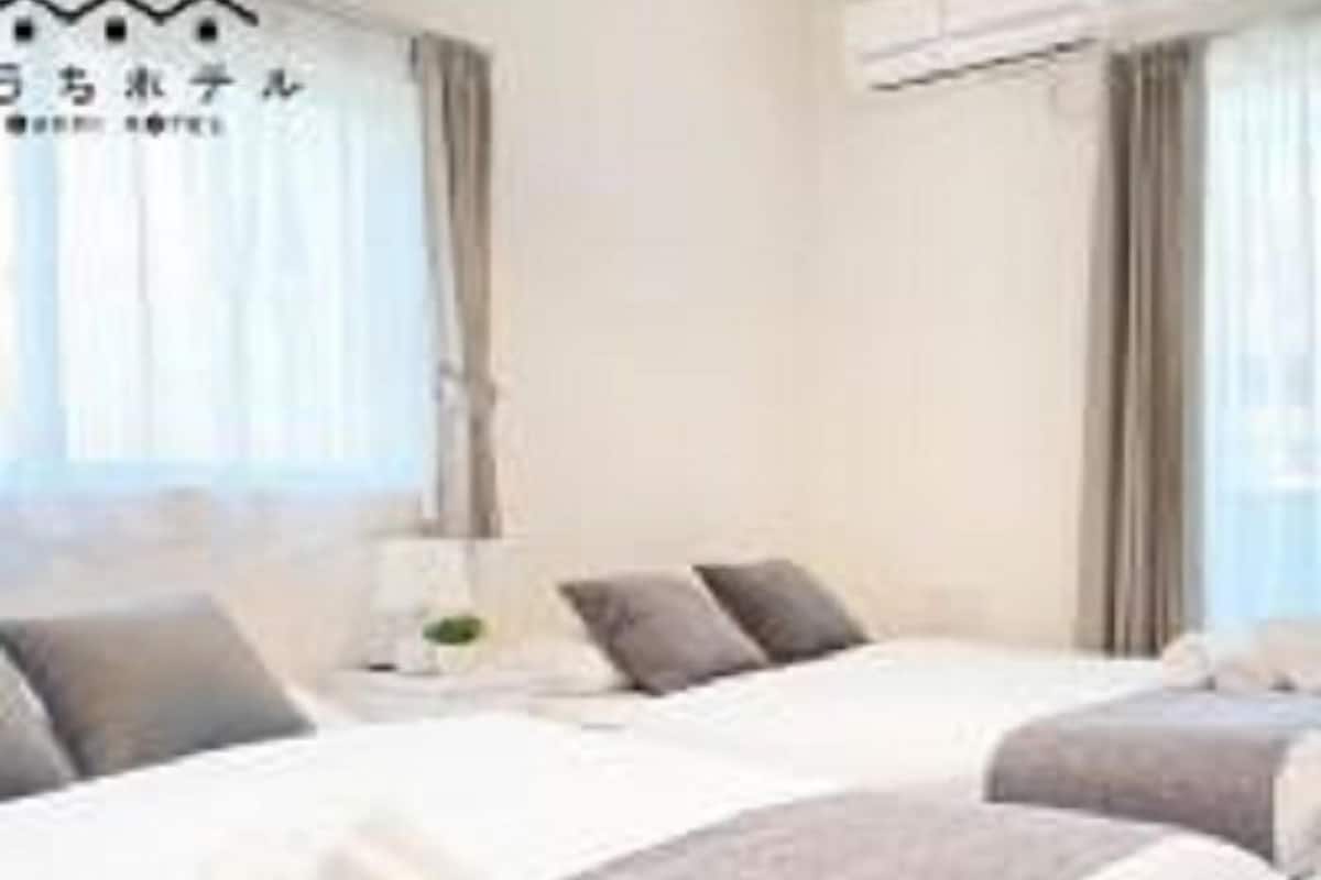 Une chambre d’hôtel avec deux lits, une table de chevet et une fenêtre avec des rideaux.