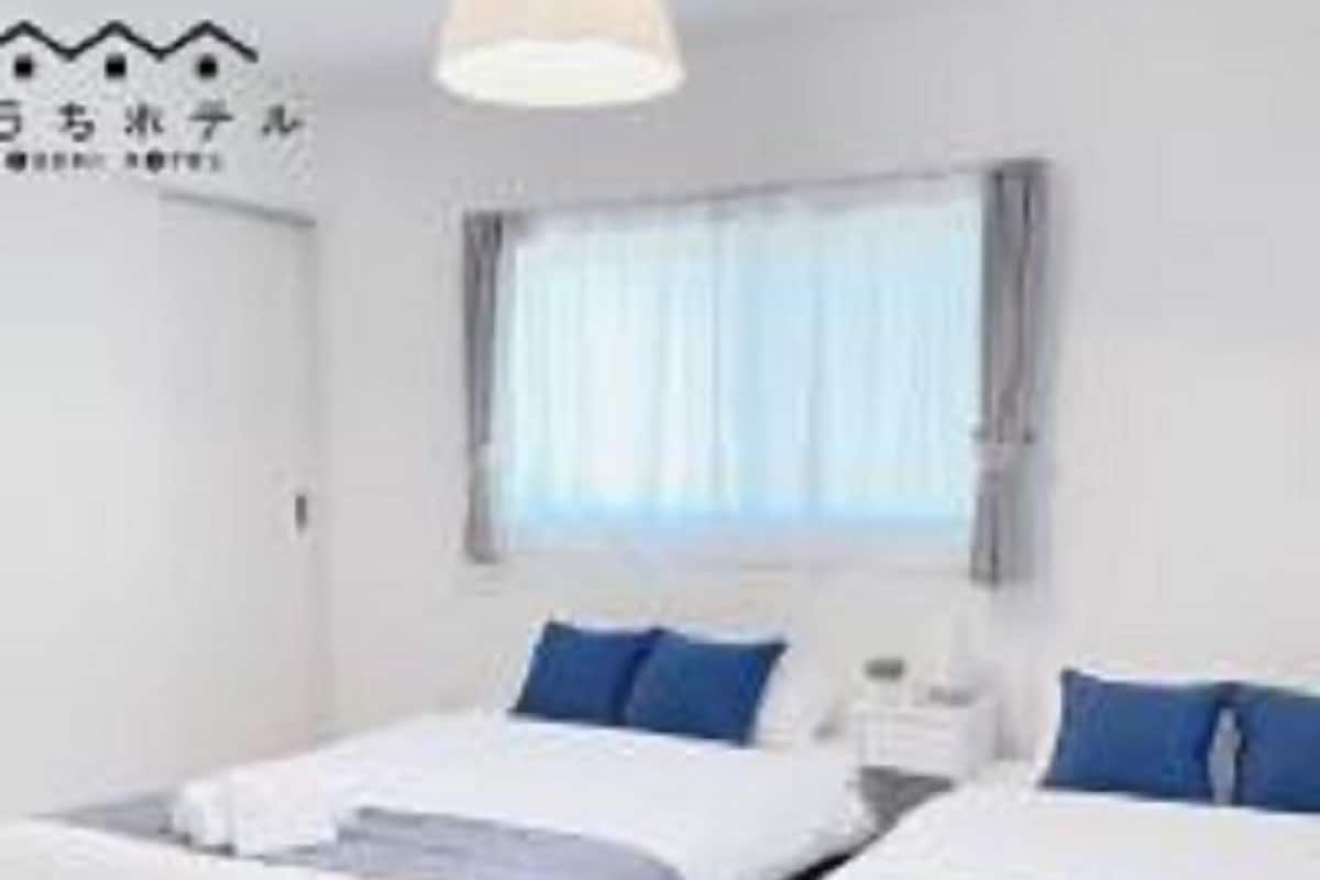 Une chambre d’hôtel avec deux lits, une fenêtre avec des rideaux et un luminaire au plafond.