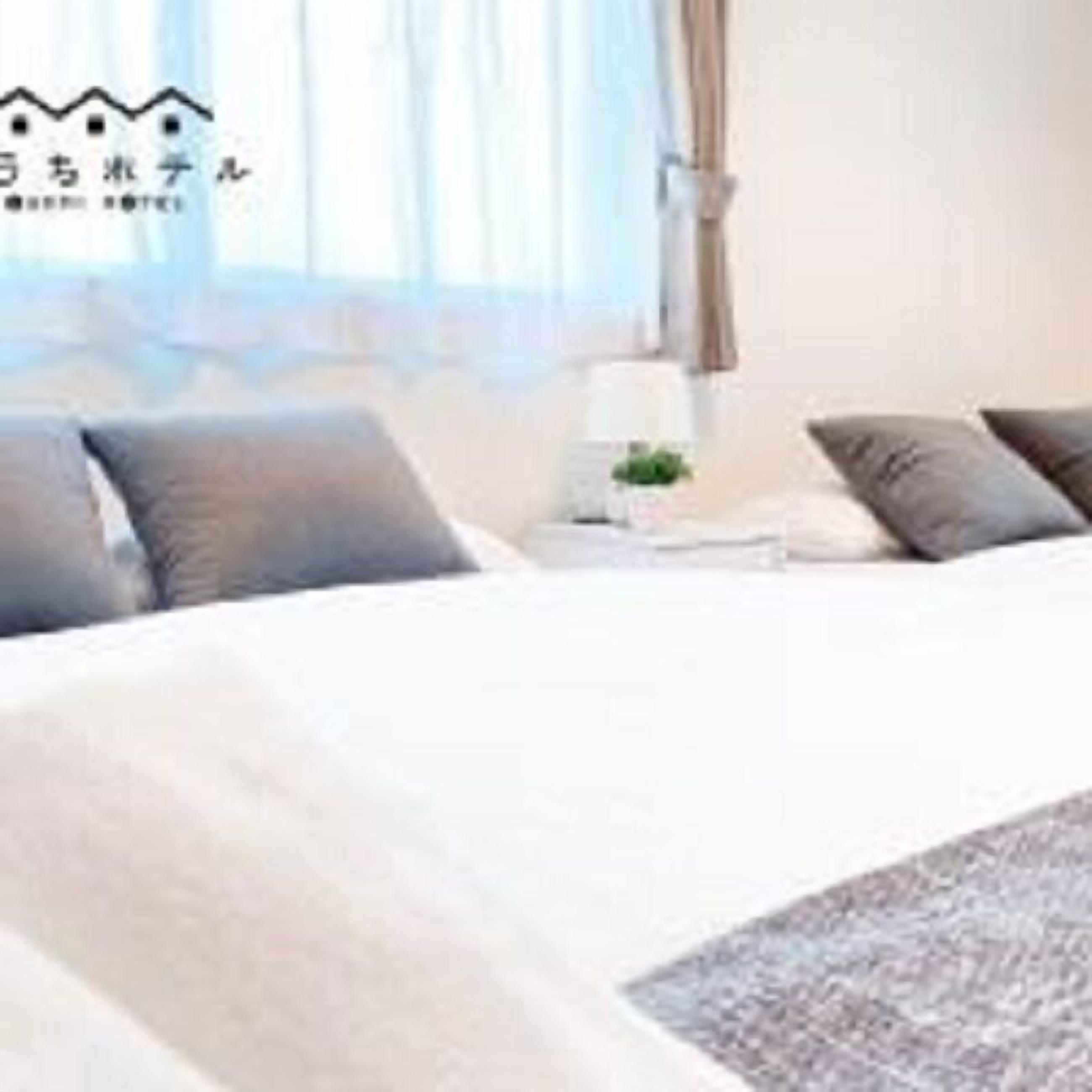 Una habitación de hotel con cama, almohadas, una mesita de noche y una lámpara.
