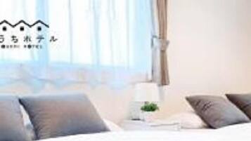 Una habitación de hotel con cama, almohadas, una mesita de noche y una lámpara.
