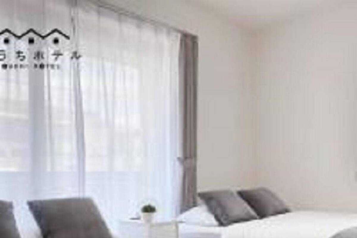 Une chambre d’hôtel avec deux lits, chacun doté d’une tête de lit grise et de draps blancs. On trouve des serviettes pliées sur les lits et une petite table avec une lampe.