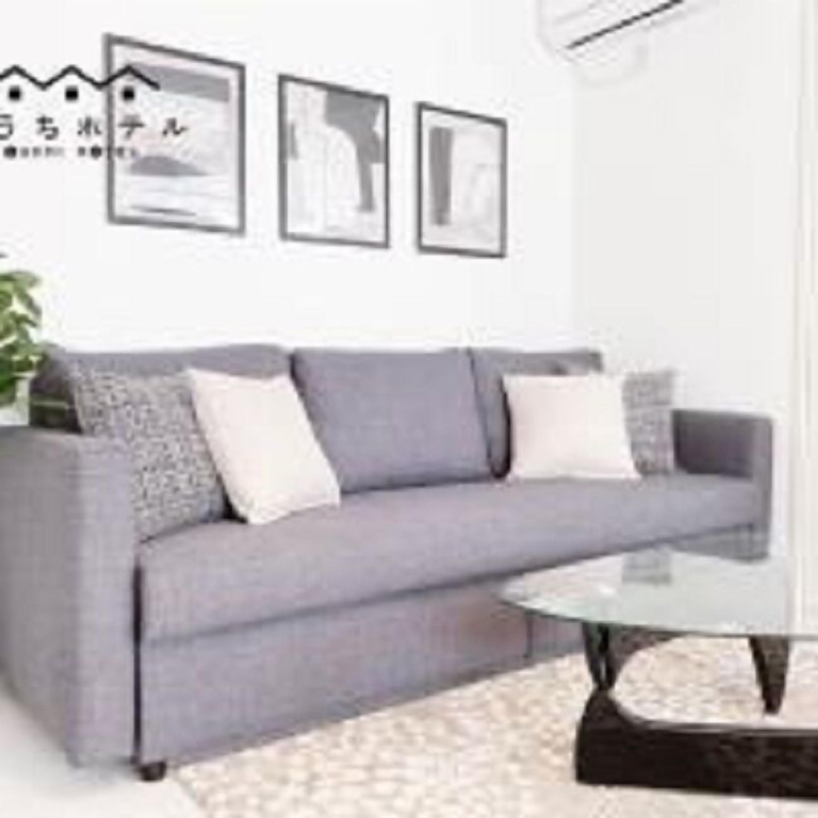 Una sala de estar moderna con un sofá gris, una mesa de centro de vidrio y obras de arte enmarcadas en la pared.
