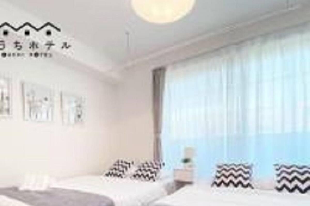 Une chambre d’hôtel avec deux lits, une grande fenêtre avec des rideaux et des œuvres d’art accrochées au mur.