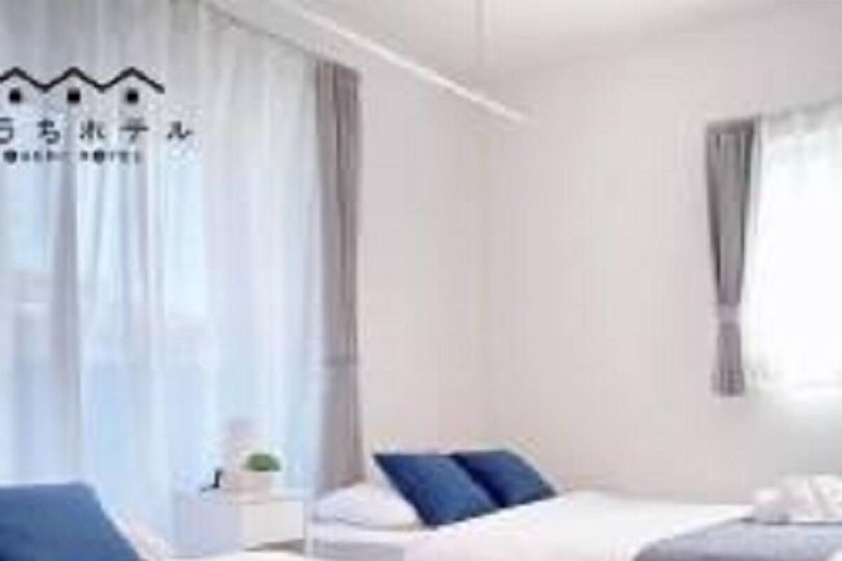 Une chambre d’hôtel avec deux lits, une table de chevet avec une lampe et une fenêtre avec des rideaux.