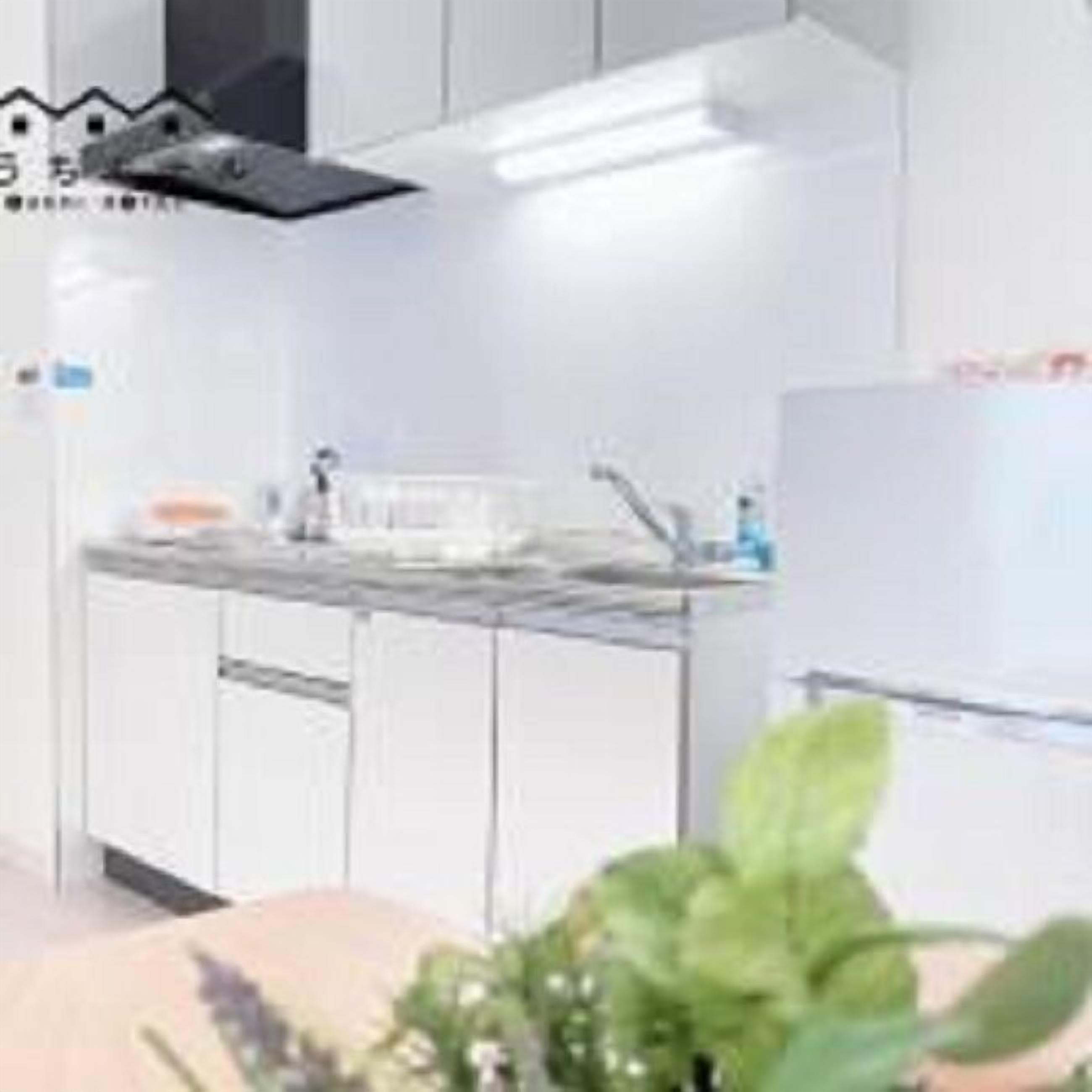 Een moderne keuken met witte kastjes, een RVS-gootsteen en een zwarte afzuigkap.