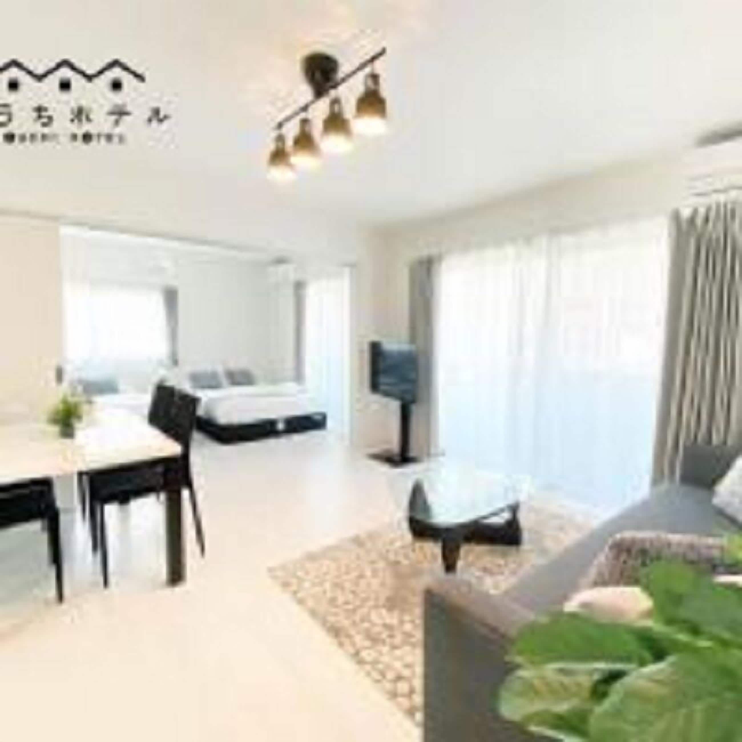 A modern hotel room with a dining area, a sofa, and a TV.