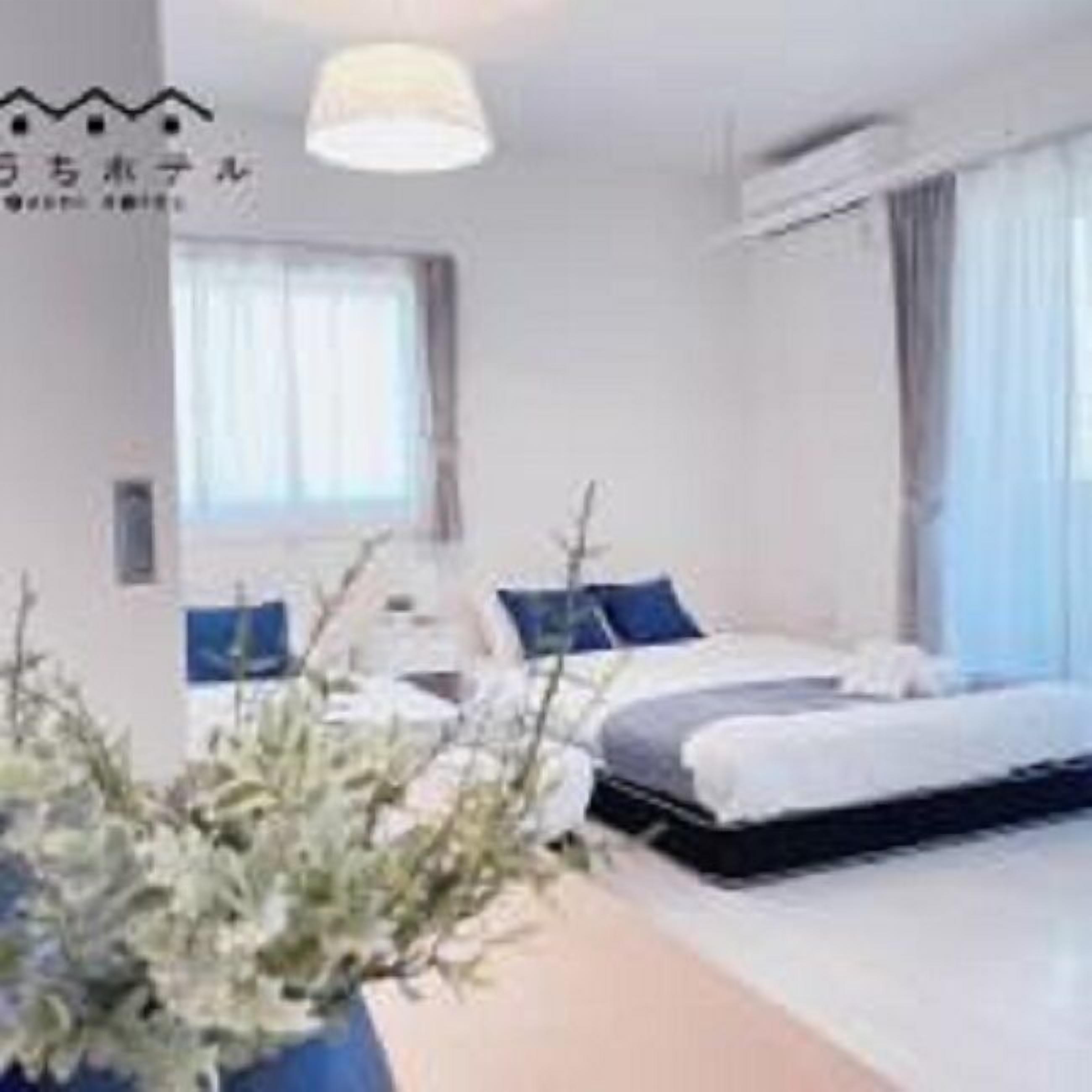 Una habitación de hotel con cama, mesita de noche y una planta en maceta.