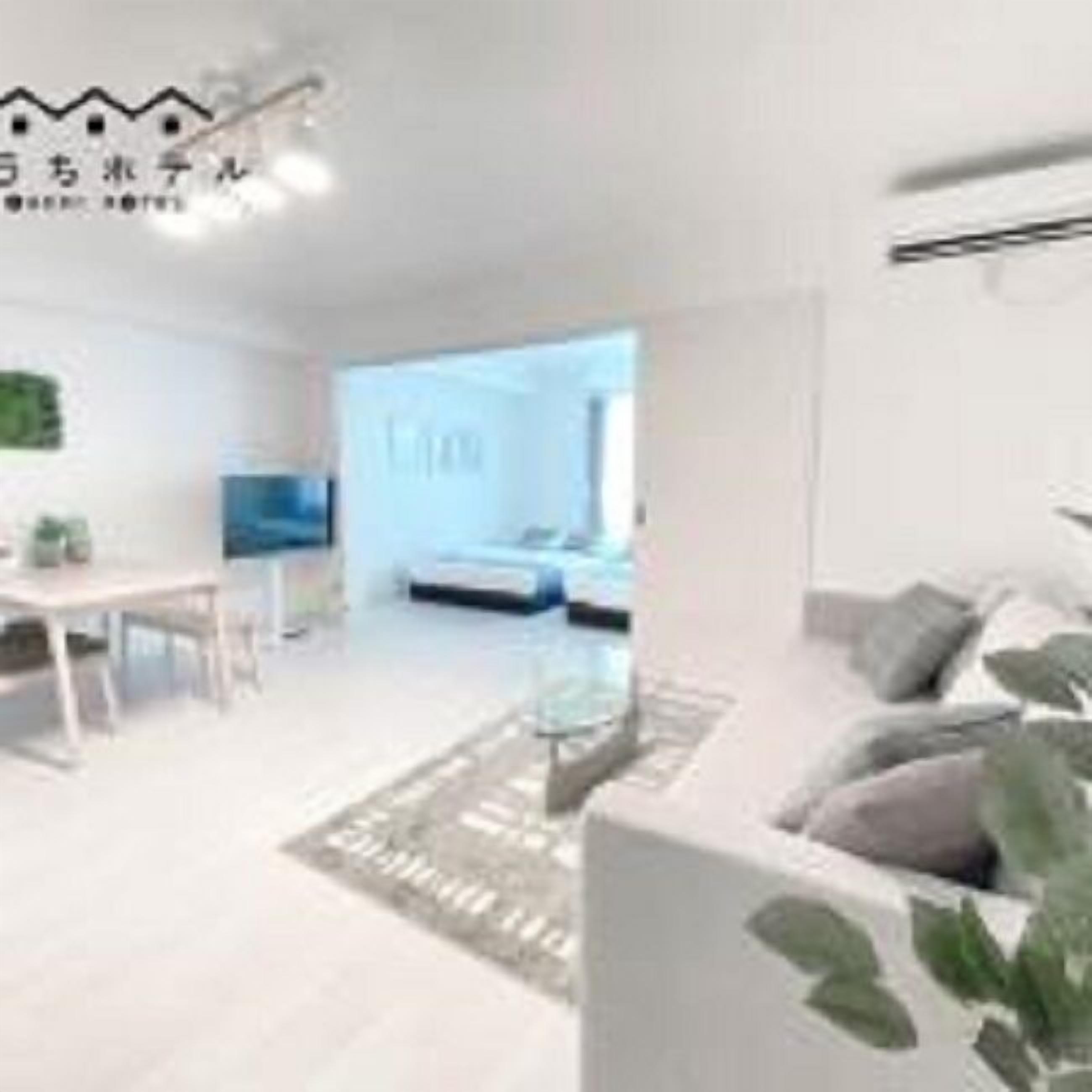 A modern living room with a sofa, coffee table, and a dining area with a table and chairs.
