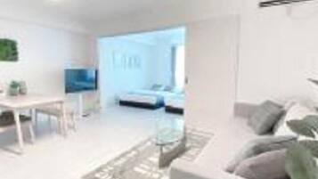 A modern living room with a sofa, coffee table, and a dining area with a table and chairs.