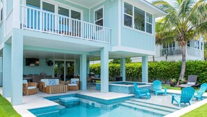 A two-story house with a swimming pool, outdoor seating, and a covered patio area. - Funky Beach Farmhouse: Beautiful Bay views, heated pool, hot tub, lounge area (Anna Maria)
