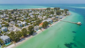 An aerial view of a coastal residential area with houses, a beach, and a pier. - Funky Beach Farmhouse: Beautiful Bay views, heated pool, hot tub, lounge area (Anna Maria)