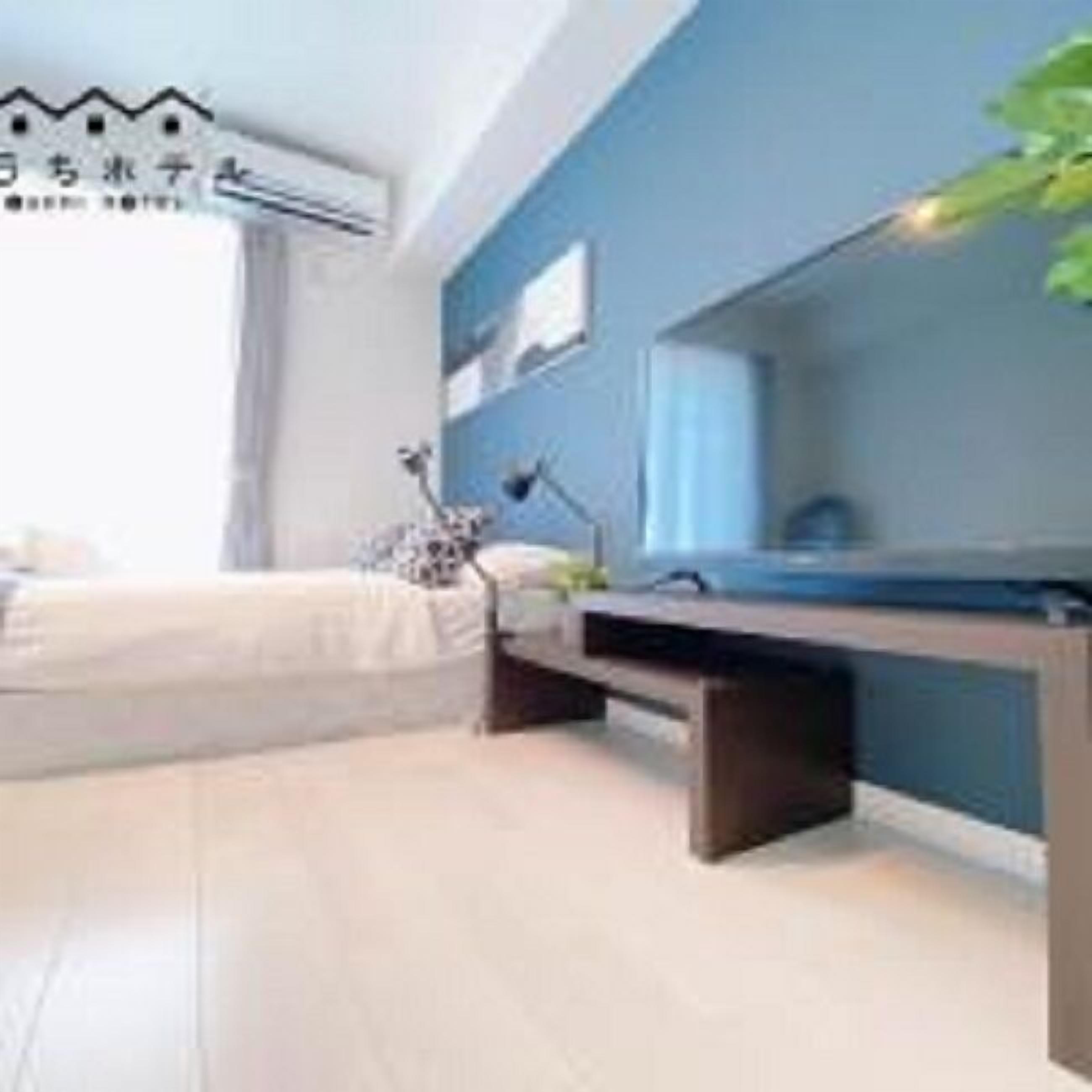 A modern bedroom with a bed, bedside table, and a desk with a chair.