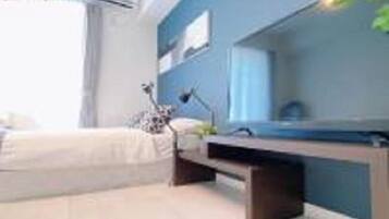 Quarto moderno com cama, mesa de cabeceira e escrivaninha com cadeira.