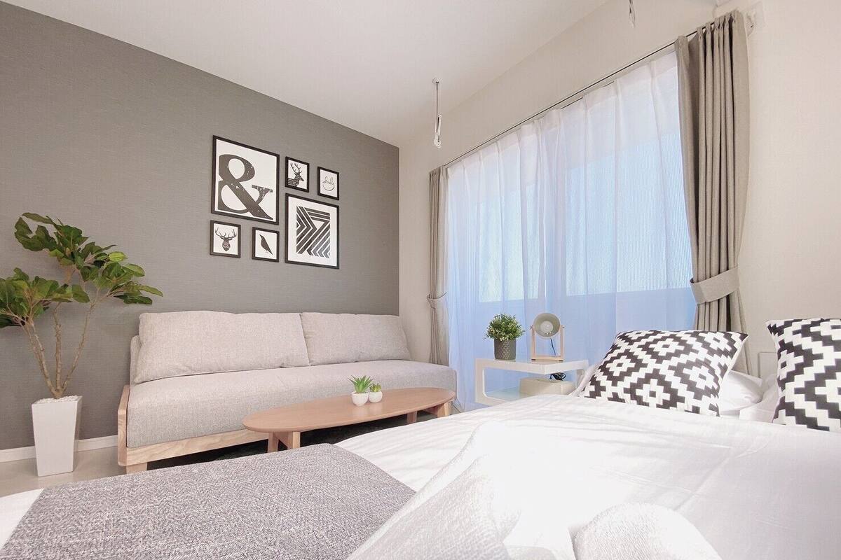 Ein modernes Schlafzimmer mit Sofa, Bett, Couchtisch und einem kleinen Beistelltisch mit Pflanze.