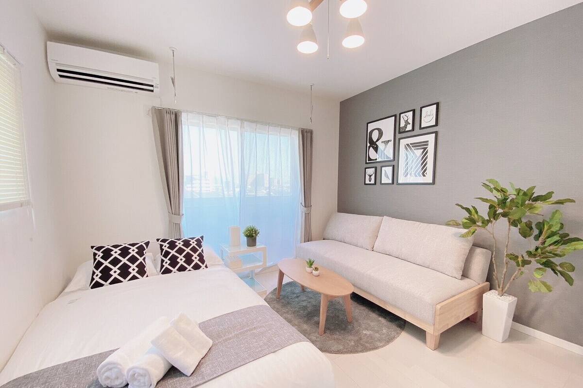 Ein modernes Hotelzimmer mit Bett, Sofa, einem kleinen Tisch und einer Zimmerpflanze.