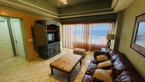 Uma sala de estar com uma mesa de centro de madeira, um sofá de couro, um armário e uma janela com cortinas.