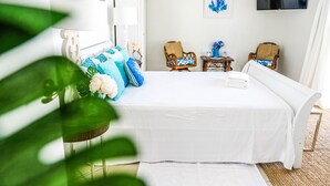 A neatly arranged bedroom with a bed, two chairs, a small table, and a TV on the wall. - Villa Azul - With a Jetted tub Villa 3 (savaneta)
