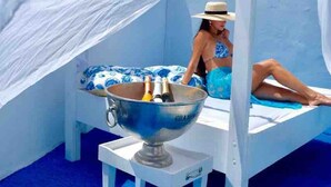 A room with a bed, a large bowl with bottles, and a person sitting on the bed. - Villa Azul - With a Jetted tub Villa 3 (savaneta)