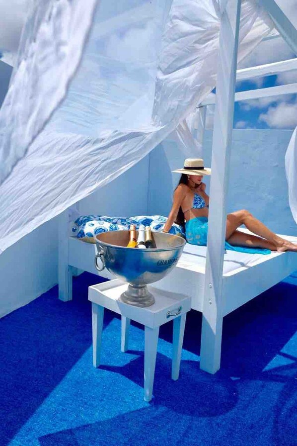 Una habitación con una cama, un cuenco grande con botellas, y una persona sentada en la cama.