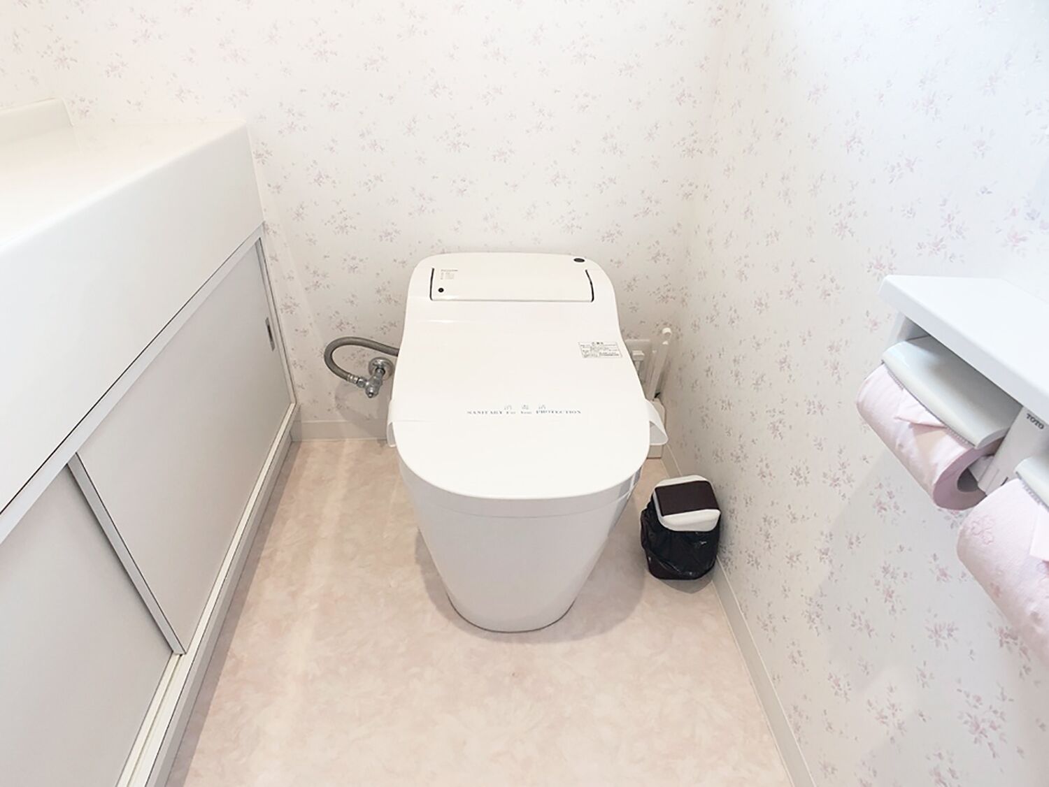 A small bathroom with a toilet, a toilet paper holder, and a trash bin.
