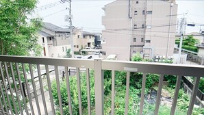 A balcony with a metal railing overlooking a residential area with multiple buildings and greenery. - Itsukaichi First Villa Hiroshima (Hiroshima)