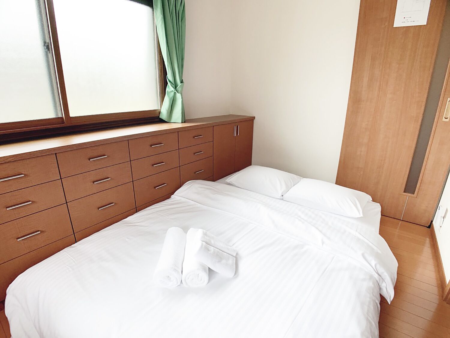Una habitación de hotel con una cama, un aparador de madera y una ventana con cortinas.