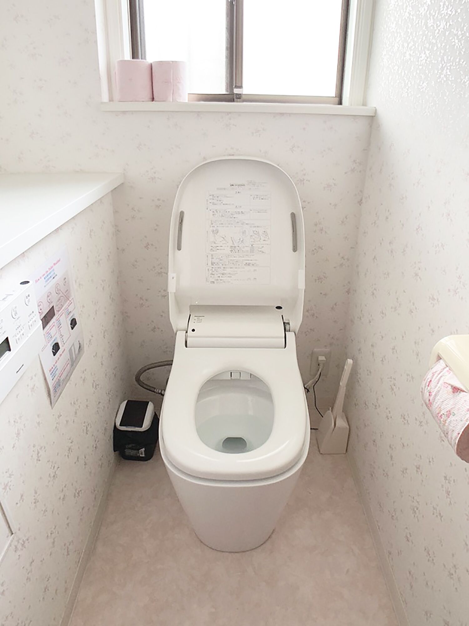 A small bathroom with a toilet, a hand dryer, and a paper dispenser.