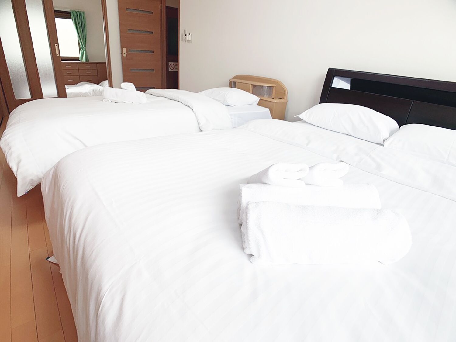 A hotel room with two beds, white linens, and neatly folded towels on the beds.