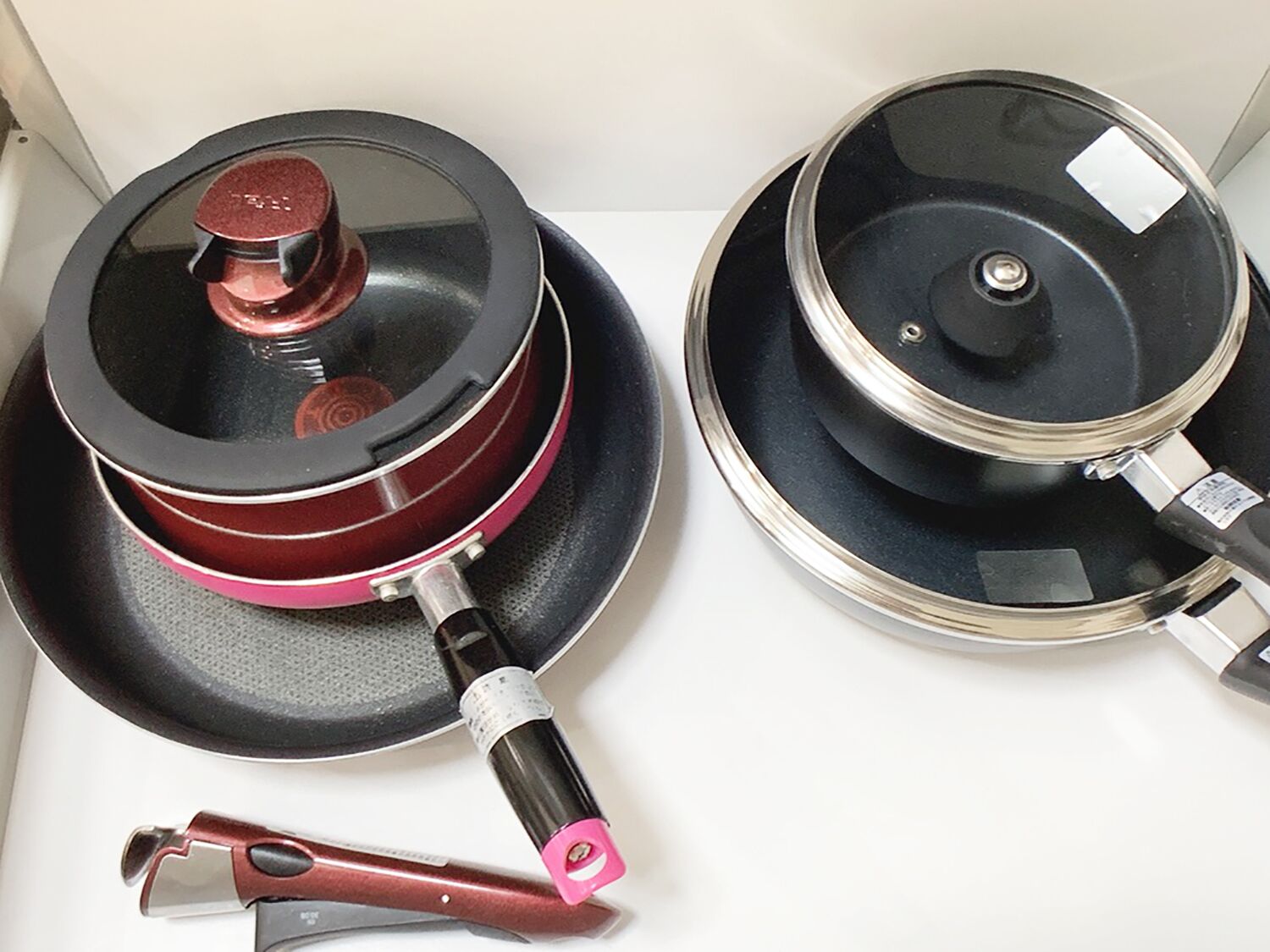 Two kitchen appliances, a pressure cooker and a frying pan, with a utensil on the left.