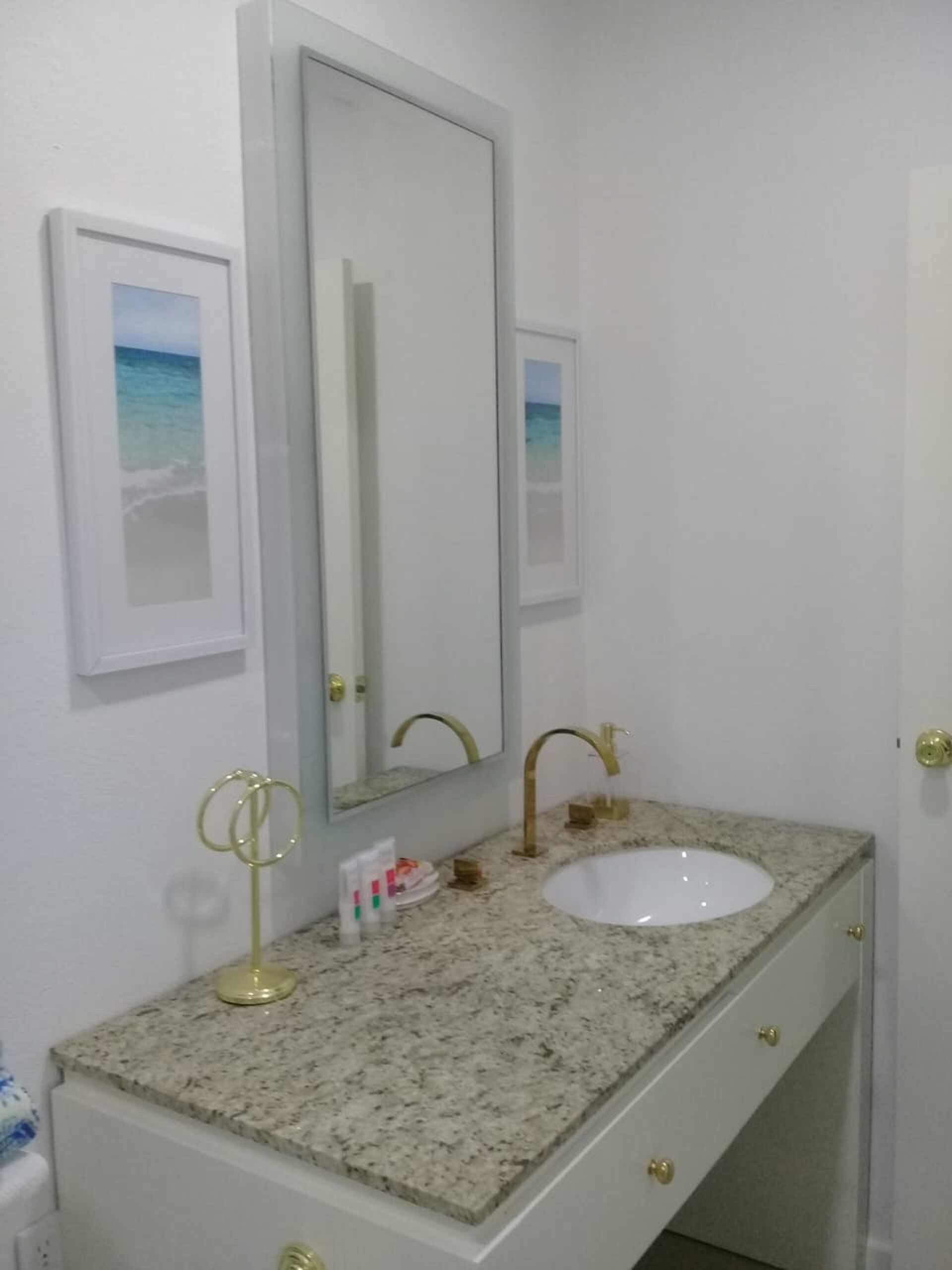 A bathroom with a granite countertop, a white sink, and a large mirror.