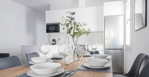 A modern dining area with a wooden table set for four, white plates, and clear glassware.