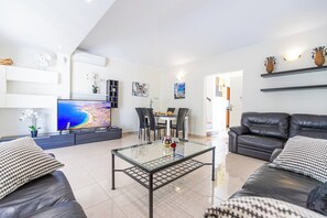 Un salon moderne avec un téléviseur à écran plat, une table basse en verre et deux canapés en cuir.
