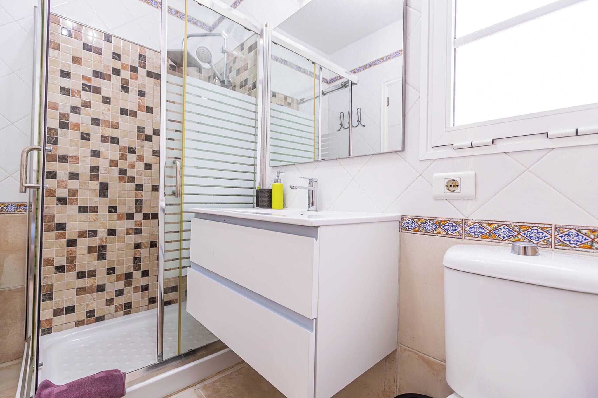 A bathroom with a glass shower enclosure, a white sink, and a toilet.