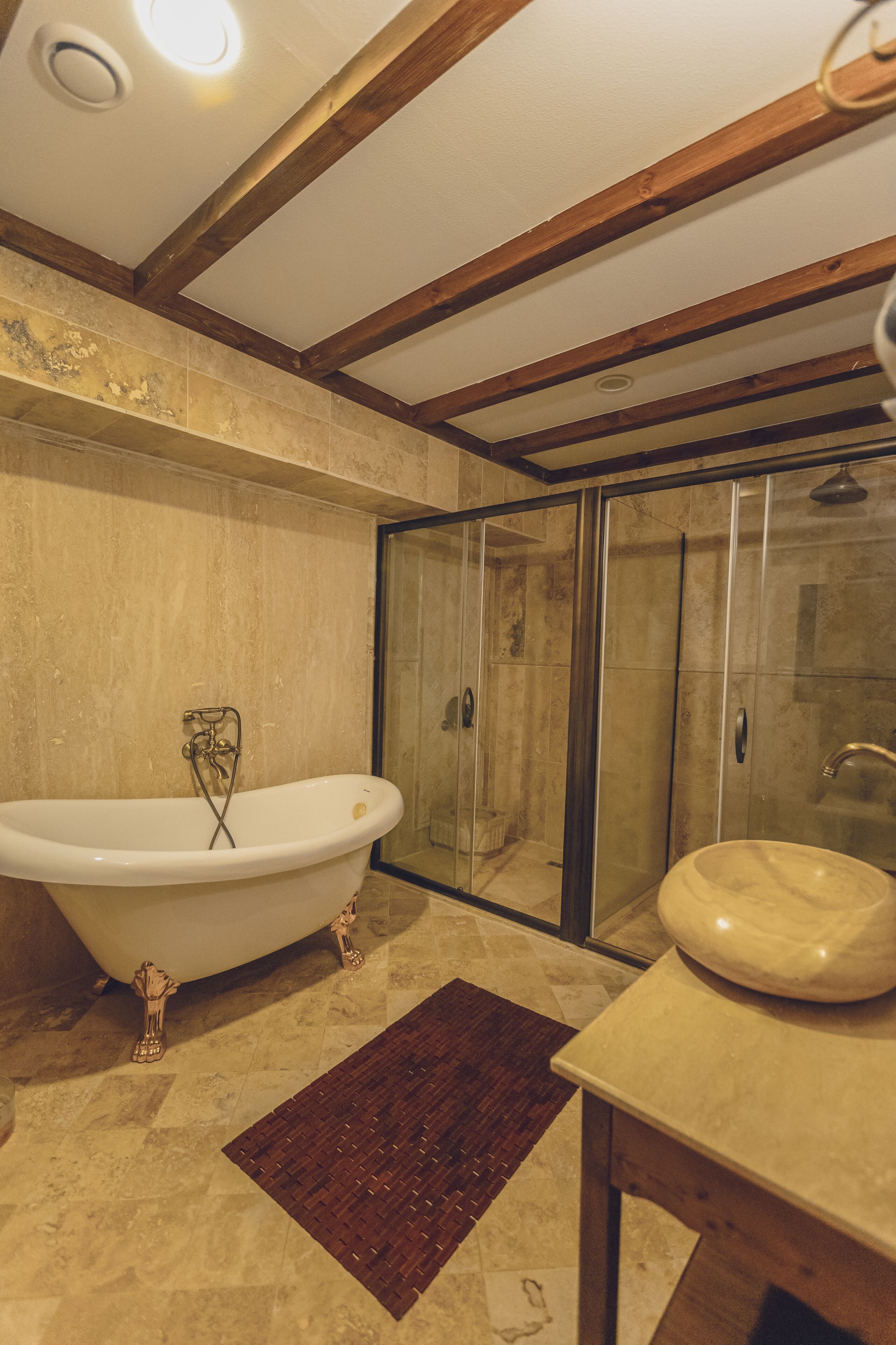 Un baño con una bañera independiente, ducha con cerramiento de vidrio y lavamanos de mármol.