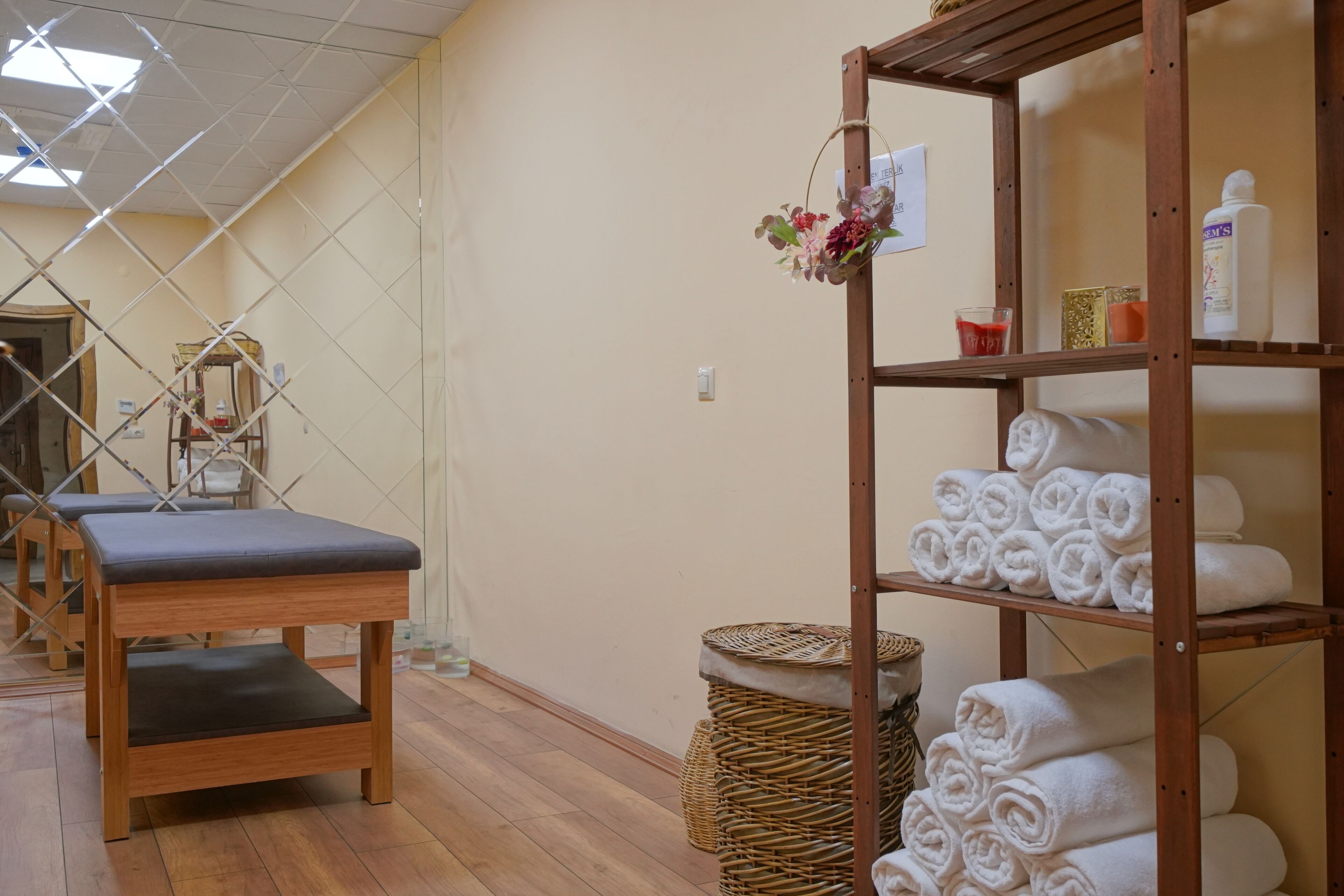 A room with wooden benches, a wicker basket, and shelves with towels and toiletries.