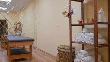 A room with wooden benches, a wicker basket, and shelves with towels and toiletries.